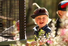 Happy Little Boy Standing Near Galah Cage With Big Smile At Nature Park