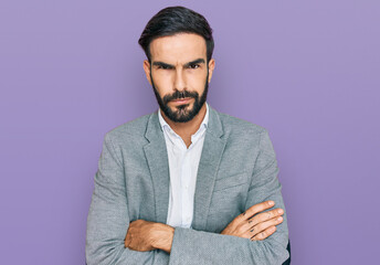 Young hispanic man wearing business clothes skeptic and nervous, disapproving expression on face with crossed arms. negative person.