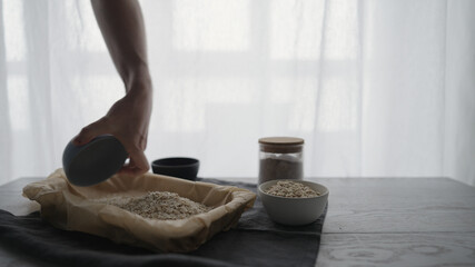 Wall Mural - Man making homemade granola with honey and different flakes on oak table