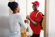 © Prostock-studio - Black Woman Receiving Grocery Shopping Bag From Courier At Home