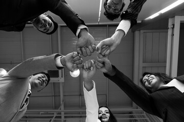 Wall Mural - close up picture of hands of multiethnic business team touching in circle for sign of unity and integrity. monochrome