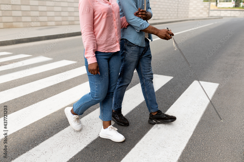 Cropped view of female caregiver assisting visually impaired black man with cane cross city street, closeup - obrazy, fototapety, plakaty 