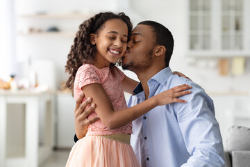 Wall Mural - Loving african american man kissing his happy little daughter