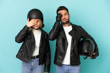 Wall Mural - Couple with motorcycle helmet over isolated blue background with surprise and shocked facial expression