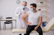 © Elnur - Young male patient visiting old male doctor in vaccination conce