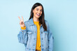 © luismolinero - Young caucasian woman isolated on blue background smiling and showing victory sign