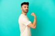 © luismolinero - Young caucasian man isolated on blue background doing strong gesture