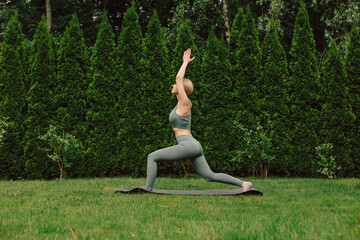 young woman practicing yoga on the grass in the garden