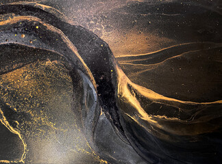 Abstract black art with gold — black background with beautiful smudges, stains and splashes made with alcohol ink. Gold fluid texture resembles space, night sky, stone, smoke, watercolor or aquarelle.