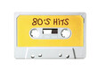 © Grenar - An old vintage cassette tape (obsolete music technology) with the handwritten text: 80's hits. White-grey plastic body and warm yellow label, isolated on white.