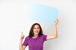 © luismolinero - Young caucasian woman isolated on white background holding an empty speech bubble with surprised expression