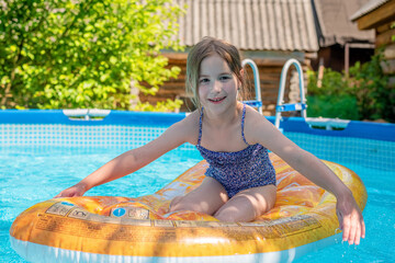 Cute little girl swims on beach air mattress in the pool