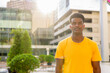 © Ranta Images - Portrait of handsome black African man wearing yellow t-shirt outdoors in city during summer backlit shot with lens flare
