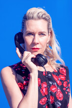 Blonde Woman In Red Dress With Retro Black Phone On Blue Background