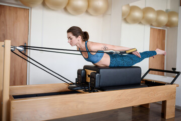 A young woman in sportswear does pilates on a reformer.Healthy Lifestyle Concept