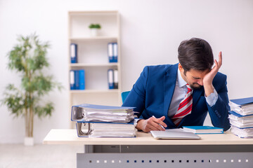 Young male employee unhappy with excessive work in the office