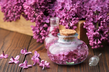 Wall Mural - Bottles of oil or infusion from purple lilac flowers on wooden table.