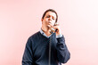 © Patricia - young adult thirty five year old man in blue v-neck shirt and sweater with pink background talking on corded phone puffing from receiving bad news