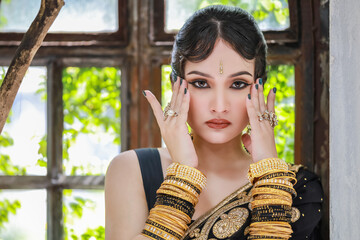 Portrait of beautiful young asian Thai girl. Woman model with black and gold traditional India costume.