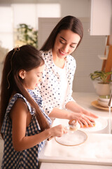 Wall Mural - Mother and daughter washing dishes together in kitchen