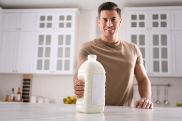 Canvas Print - Man with gallon bottle of milk at white marble table in kitchen