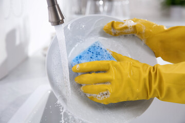 Canvas Print - Woman washing plate in modern kitchen, closeup