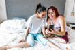 latin girl with cerebral palsy with her mother holding a phone on bed at Home in disability concept in Latin America