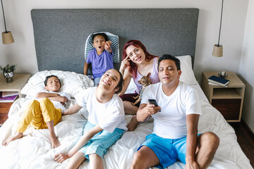 Canvas Print - latin family and girl with cerebral palsy watching tv on bed at Home in disability concept in Latin America