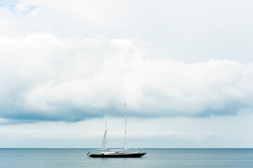 Canvas Print - Stunning view of a luxury sailboat sailing on a beautiful calm sea during a dramatic, cloudy day. Costa Smeralda, Sardinia, Italy. Recreational pursuit, copy space.