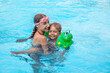 Happy brother and sister swim in the pool. Smiling girl and boy are playing in the pool. The concept of family vacation or relaxation in the pool or the sea.