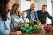 © Halfpoint - Happy multigeneration family indoors at home preparing vegetable salad.