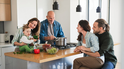 Happy multigeneration family indoors at home cooking together.