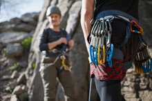 Unrecognizable Instructor With Harness And Carabiners Climbing Rocks With Seniors Outdoors In Nature, Active Lifestyle.