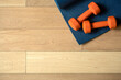 Yoga and fitness background. Wooden floor parquet or laminate with rug and dumbbells for training in a yoga room or gym