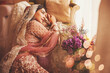 Gorgeous vintage style Indian bride sitting in a luxury hotel room wearing traditional lehenga with ghungat