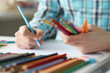 © H_Ko - Female hands hold multi-colored pencils and sheet of paper lies on table