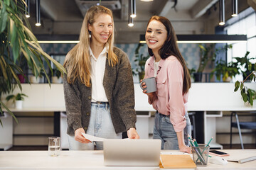 Wall Mural - Two young women working together in office