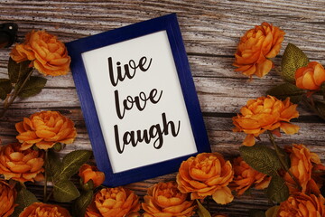 Love Live Laugh typography text with flower decoation on wooden background