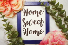 Home Sweet Home Written On Blue Frame With Green Leave And Pink Flower Flat Lay On Marble Background