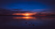 Sonnenuntergang im Sommer an einem großen, spiegelglattem See in wunderschöner, stiller Atmosphäre am Abend mit Enten im Vordergrund