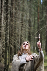 A man in a cassock spends a ritual in a dark forest