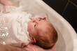 © RasaBasa - Baby girl, infant bathing. Father hands holding newborn securely. First-time parents, baby-care concept.