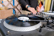 © Galina - Vinyl record spinning on a turntable. DJ at the music desk during a DJ set on the terrace of a trendy youth bar.