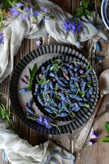 Wall Mural - A vertical view of a metal bowl with ripe juicy blue berries on a gray rustic background. View from above