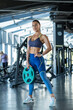 © nazarovsergey - Confident fit girl standing with weight plate at gym