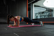 © nazarovsergey - Fit girl doing front elbow plank on mat at gym