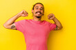 © Asier - Young caucasian man with long hair isolated on yellow background stretching arms, relaxed position.