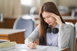 © EduLife Photos - Young desperate and stressful Asian woman student in student uniform doing examination assignment in a college university classroom alone