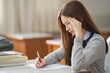 © EduLife Photos - Young desperate and stressful Asian woman student in student uniform doing examination assignment in a college university classroom alone