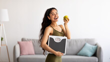 Portrait Of Millennial Indian Lady Holding Scales And Eating Apple, Choosing Healthy Diet, Panorama